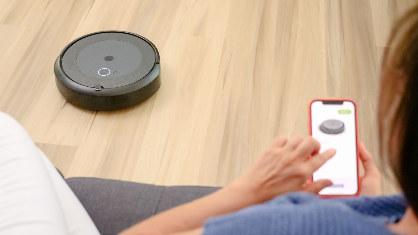Persona controlando un robot aspirador con una app del móvil