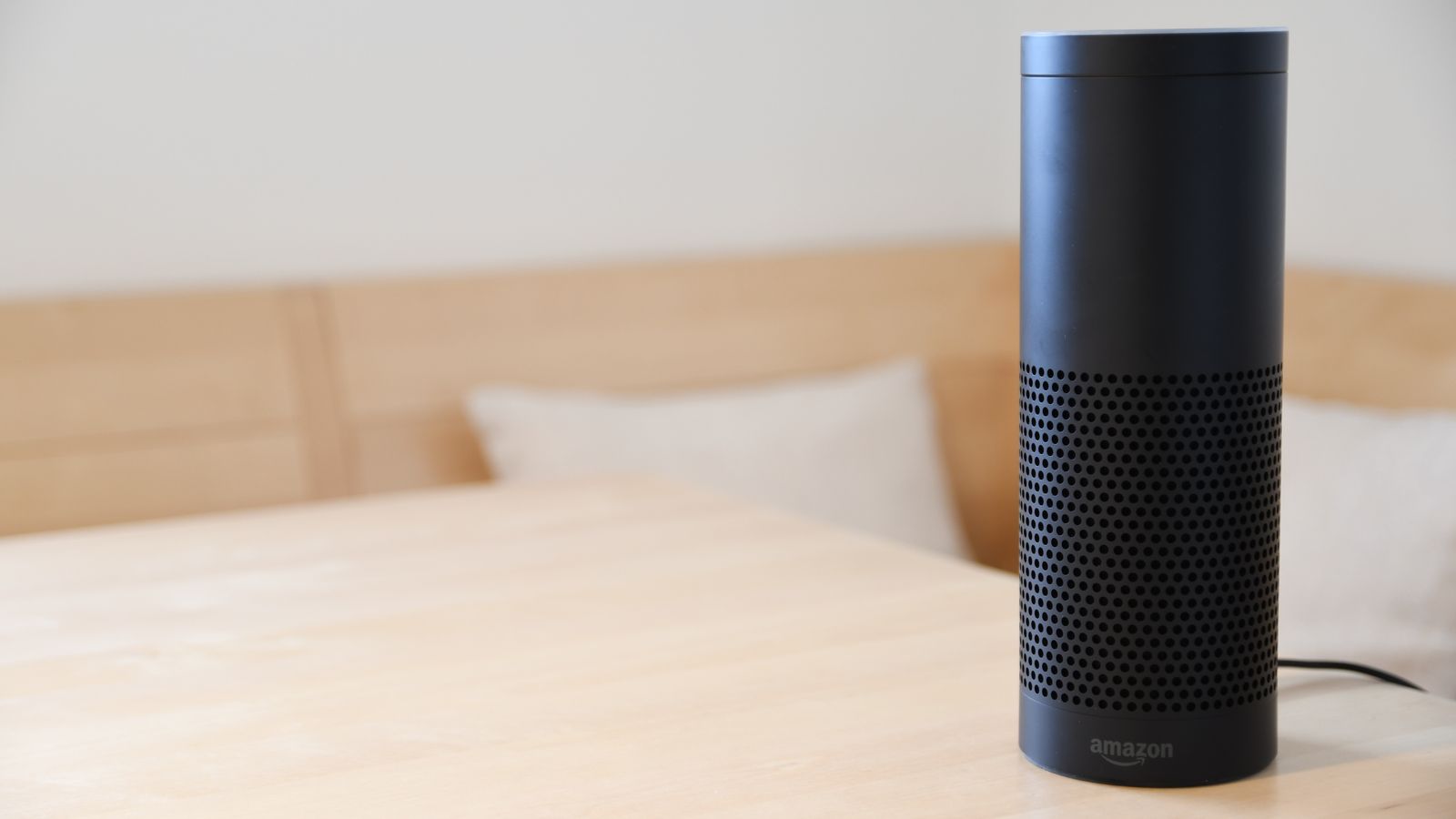 Altavoz inteligente negro sobre una mesa de madera clara en un salón